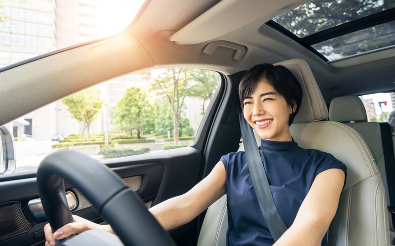 Smiling woman driving car with sunroof.